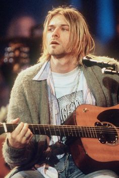 a man sitting in front of a microphone holding a guitar