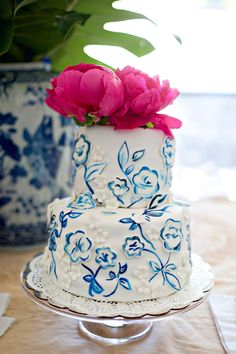 a white and blue cake with pink flowers on top