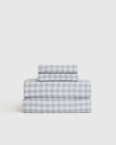 the gingham sheet set in grey and white is folded on top of each other