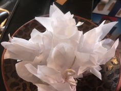 white tissue flowers in a brown bowl on a counter top with other items around it