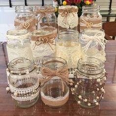 mason jars with lace and burlocks are sitting on a table