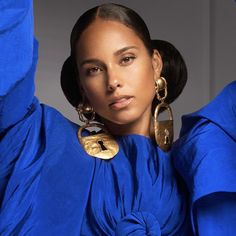 a woman with large gold hoop earrings on her head and wearing blue clothing, posing for a photo