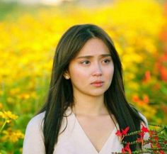 a woman standing in a field with flowers