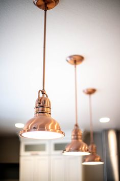 three light fixtures hanging from the ceiling in a room with white walls and flooring