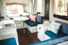 the inside of a camper with blue couches and white table in front of it