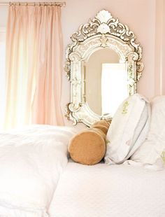 a teddy bear sitting on top of a bed next to a mirror and pillows in front of it