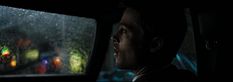 a man sitting in the back seat of a car while it is raining with rain