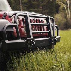 a red jeep parked on top of a lush green field