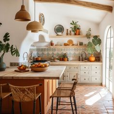 a kitchen with an island, potted plants and two chairs