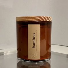 a candle with a label on it sitting on a glass table next to a white wall