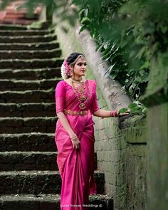 a woman in a pink sari standing on some steps