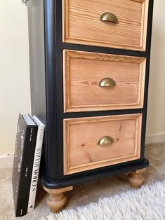 an old dresser has been painted black with gold hardware and is next to a book