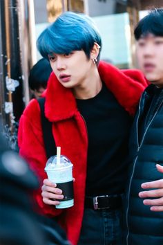 two young men standing next to each other with blue hair and one holding a drink