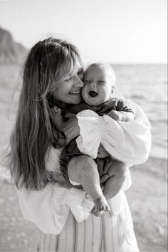 a woman holding a baby on the beach