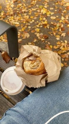 a person's hand holding a pastry wrapped in brown paper