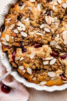 a pie with cranberries and almonds in a white dish on a table