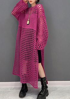 a woman standing in front of a wall wearing a pink crochet sweater and black boots