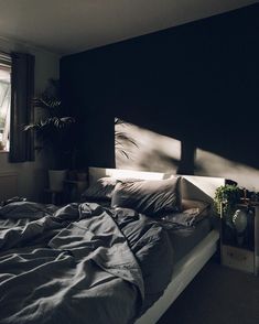 an unmade bed sitting in a bedroom next to a window with the sun shining on it