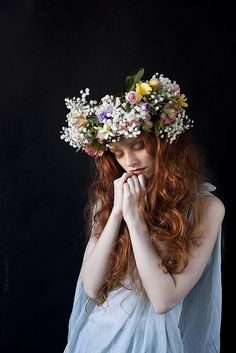 a woman with long red hair wearing a wreath of flowers on her head is posing for the camera