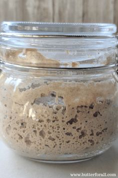 a glass jar filled with food sitting on top of a white counter next to a wooden wall