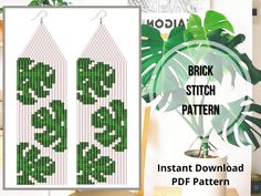 a pair of earrings with green leaves on them and the words brick stitch pattern next to it