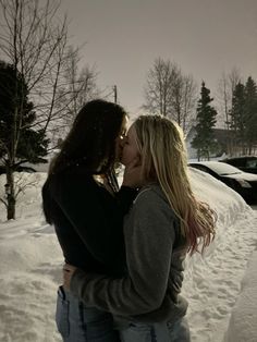 two women standing in the snow kissing each other