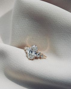 an engagement ring with three diamonds on it sitting on top of a white cloth surface