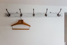 a coat hanger is hanging on the wall next to a pair of wooden clothes hangers