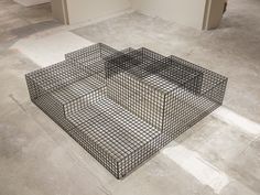 a metal cage sitting on the floor in an empty room with no people around it