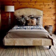 a bed with pillows and blankets on it in a room that has wood paneled walls