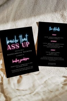 two black cards with neon lights on them sitting on top of a white bed sheet