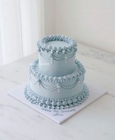 three tiered blue cake sitting on top of a white table