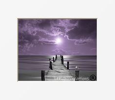 a pier in the middle of an ocean under a purple sky with clouds above it