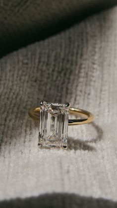 an emerald - cut diamond ring sits on a blanket