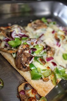 two slices of pizza sitting on top of a metal pan covered in cheese and veggies