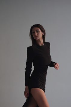 a woman is posing in a black dress and high heeled boots for the camera