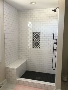 a white tiled bathroom with black and white tiles on the shower wall, floor and walls