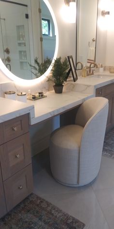 a bathroom with a vanity, stool and large round mirror on it's wall