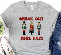 "Looking for a funny Christmas shirt that will make you the life of the party? Look no further than Deez Nuts! This hilarious t-shirt features colorful nutcrackers standing in a line with festive red and green outfits. Plus, the slogan \"check out deez nuts\" is sure to get a laugh from anyone who sees it. So put on your jolly best and order Deez Nuts funny Christmas shirt today! Soft cotton and quality print make users fall in love with it over and over again. These t-shirts have-ribbed knit co Christmas T-shirts Vinyl Funny, Funny Christmas Shirts Inspire Uplift ⭐, Cute Christmas Shirts Funny Saying, Cheap Christmas T-shirt With Funny Print, Cheap Funny Christmas Tops, Cheap Christmas Tops With Funny Text, Cricut Christmas Work Shirts, The Lucky Few Christmas Shirt, Funny Christmas Shirts Zazzle