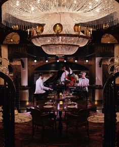 a group of people sitting around a table in front of a chandelier