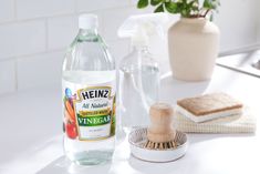 a bottle of heinzz all natural vinegar next to a brush and sponge on a counter