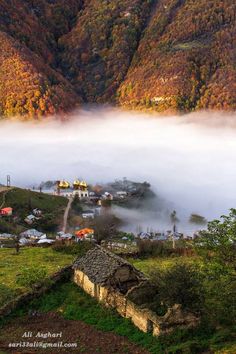 the mountains are covered in fog and low lying clouds, with small houses on top