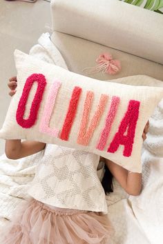 a woman laying on top of a bed holding a pillow with the word alive written on it