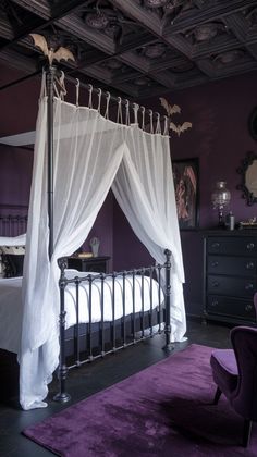 a bedroom with purple walls and white drapes on the canopy over the bed,