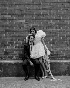 a man and woman pose for a photo in front of a brick wall