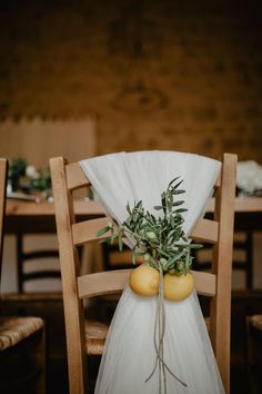 two lemons tied to the back of a chair with greenery on top and white cloth draped over them