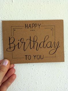 a hand holding up a brown card with the words happy birthday to you on it