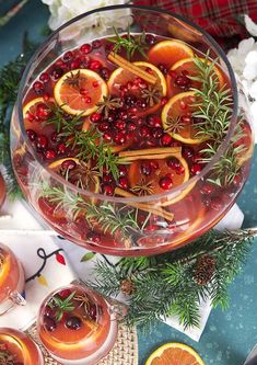 a bowl filled with oranges and cranberries on top of a table