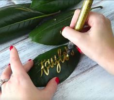 a woman is writing on a leaf with gold lettering