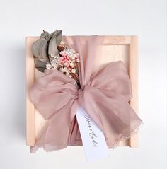 a wooden box with a pink bow and flowers in it